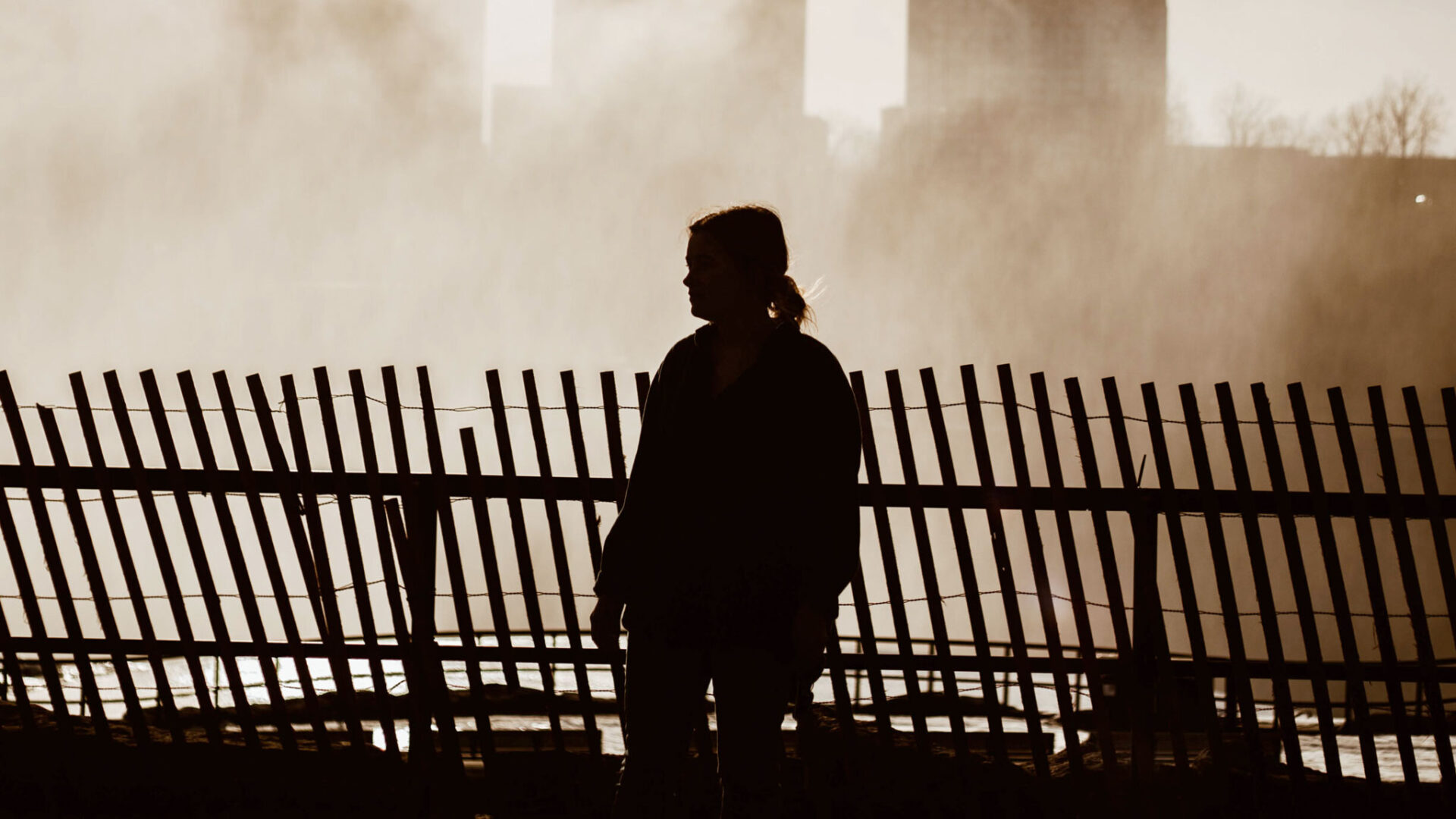 Woman walking along wooden fence