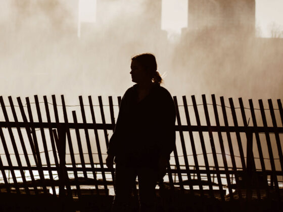 Woman walking along wooden fence