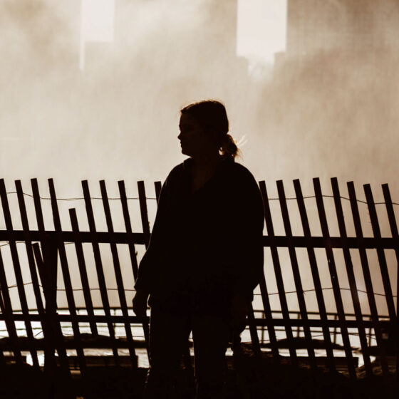 Woman walking along wooden fence