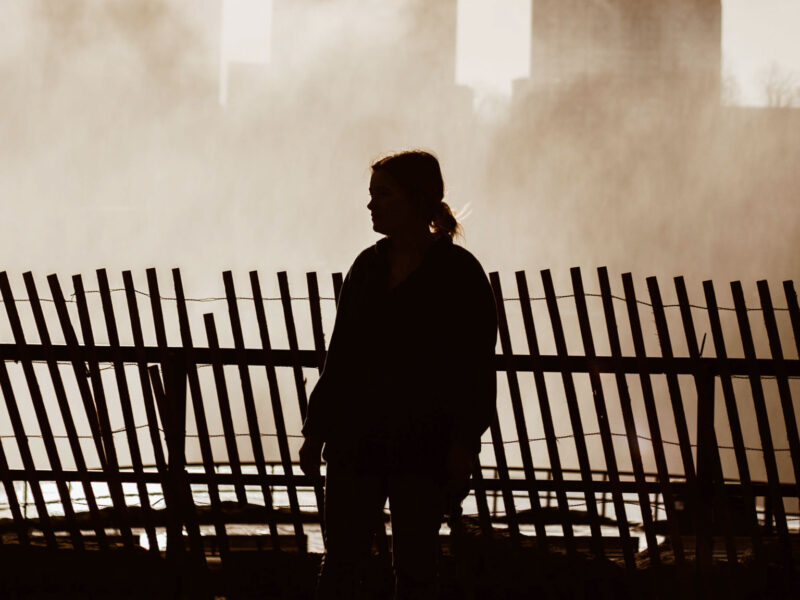 Woman walking along wooden fence