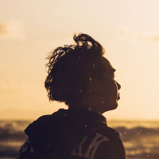 Man looking out at water at sunset