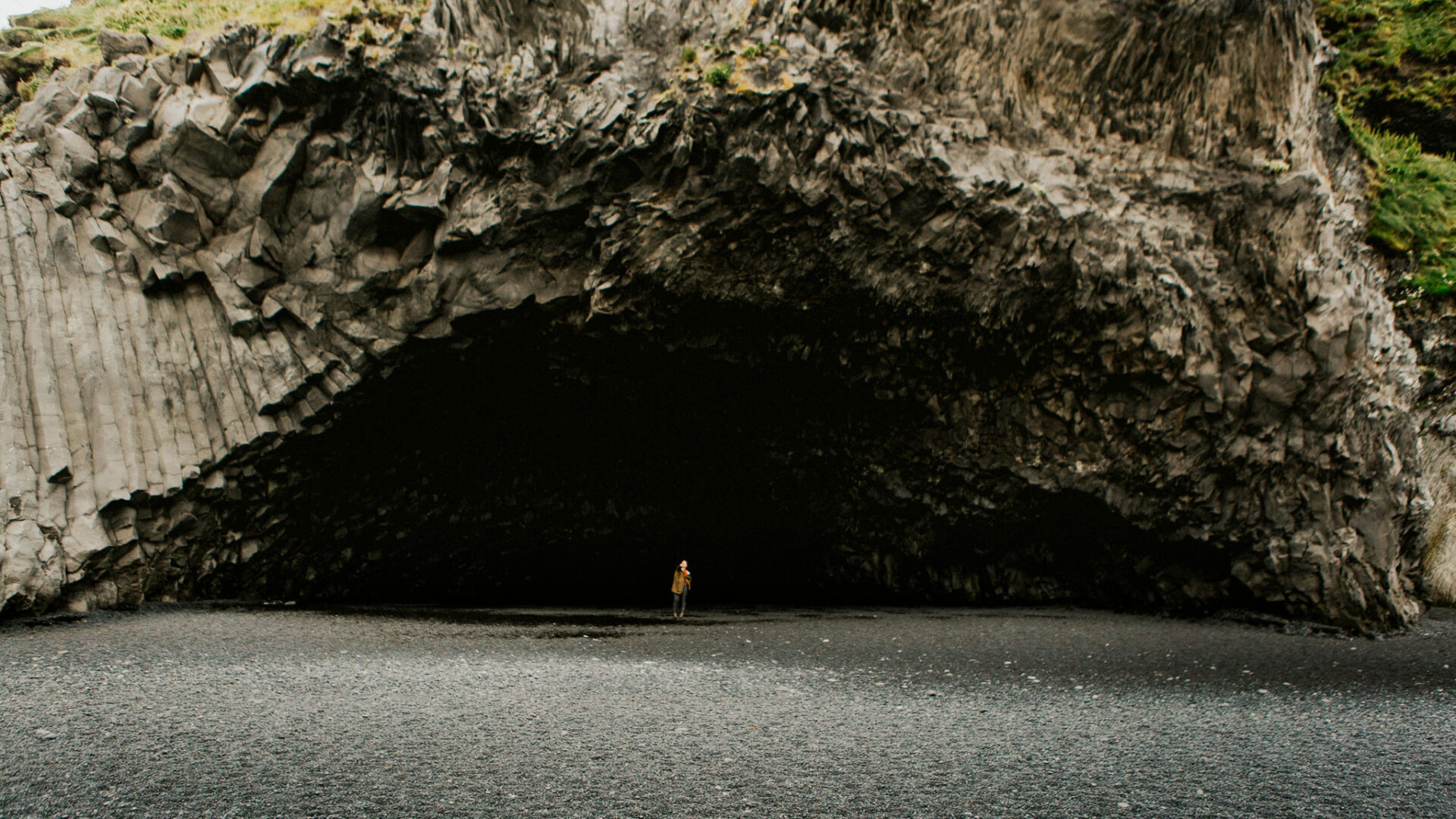 Person standing in large cave entrance