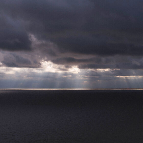 Sun rays shining through dark clouds over water