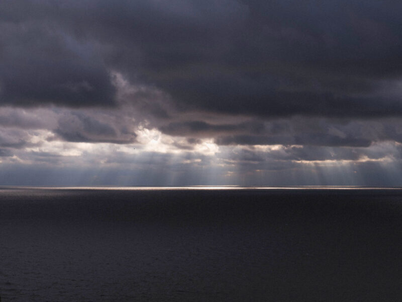Sun rays shining through dark clouds over water