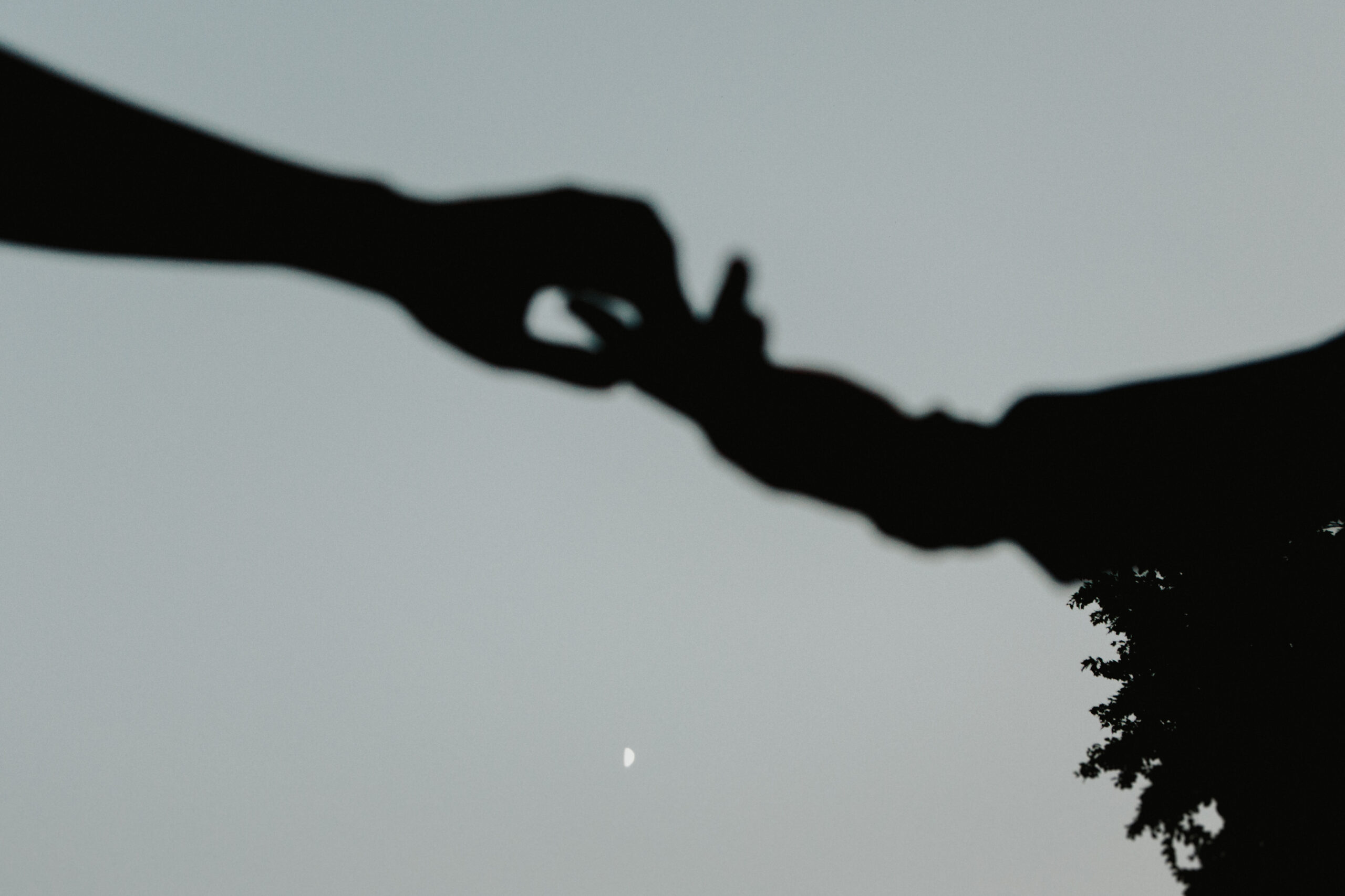 Silhouette of two hands reaching for one another