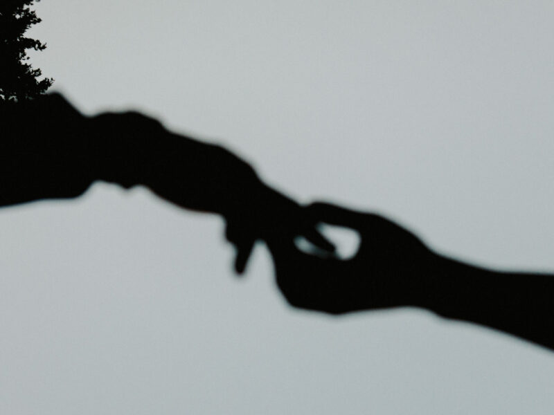 Silhouette of two hands reaching to one another
