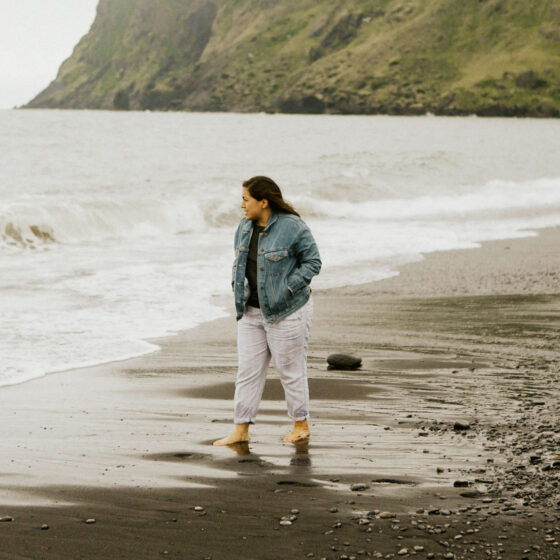 Woman in jacket walking along beach