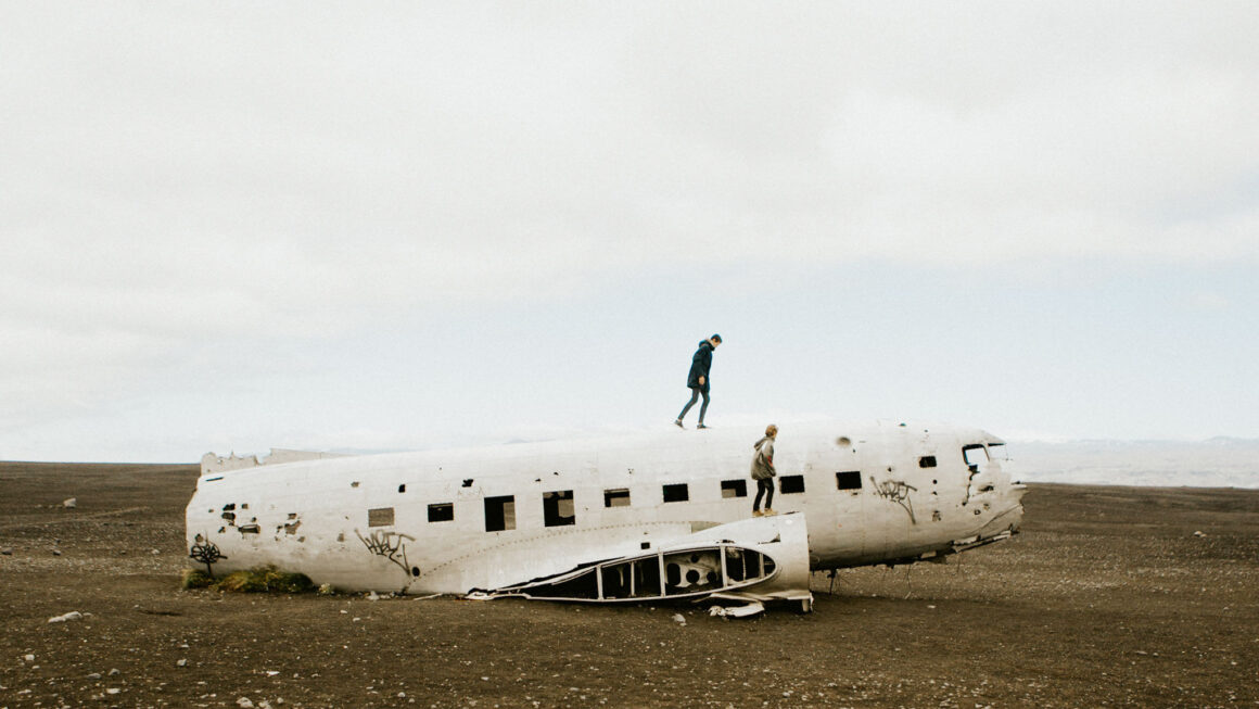 Two people climbing a broken, abandoned plane
