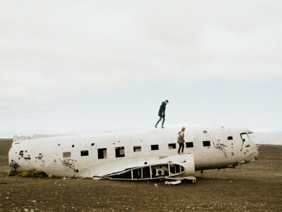 Two people climbing a broken, abandoned plane