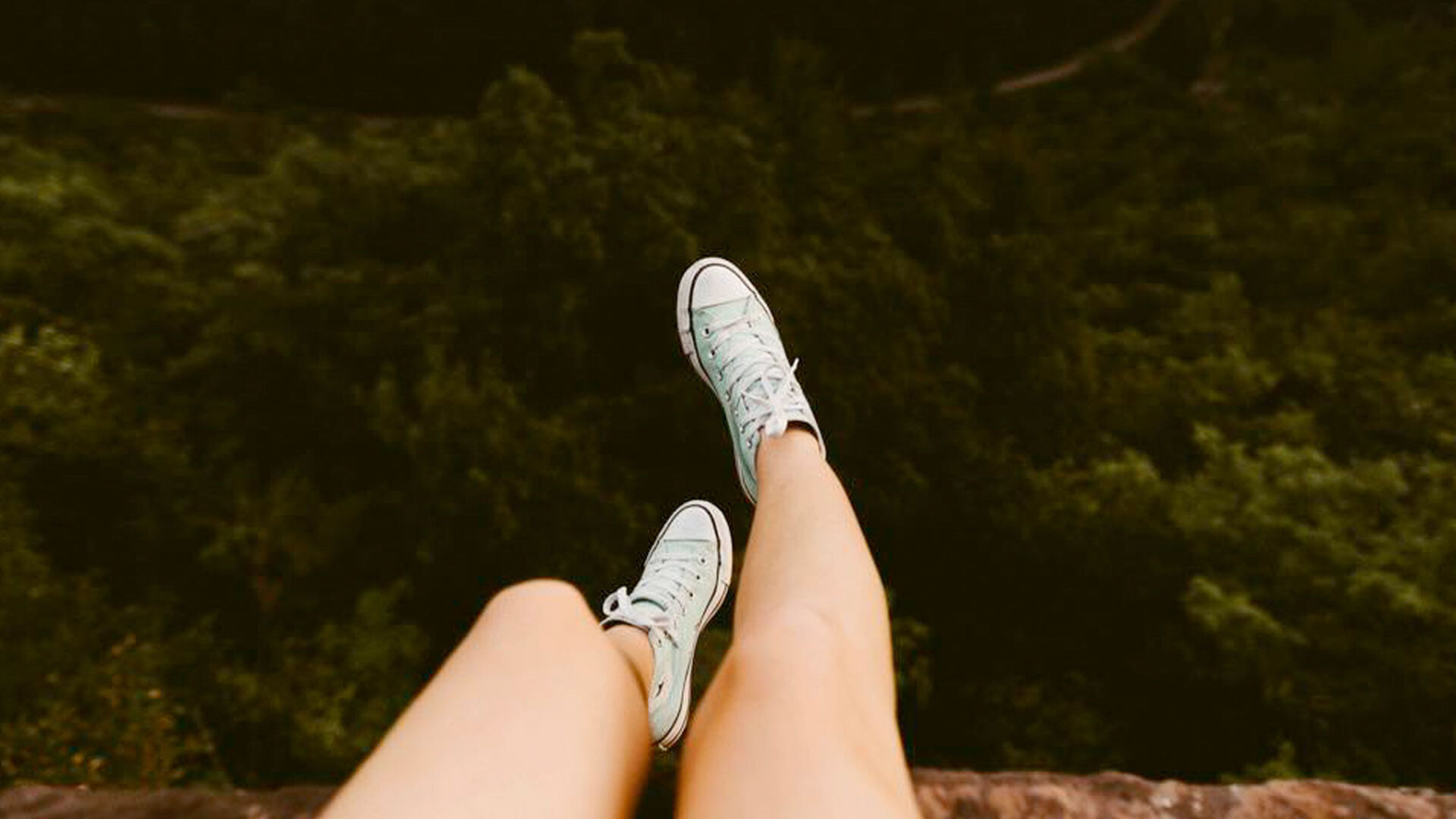 Girls legs and feet dangling over edge of a cliff