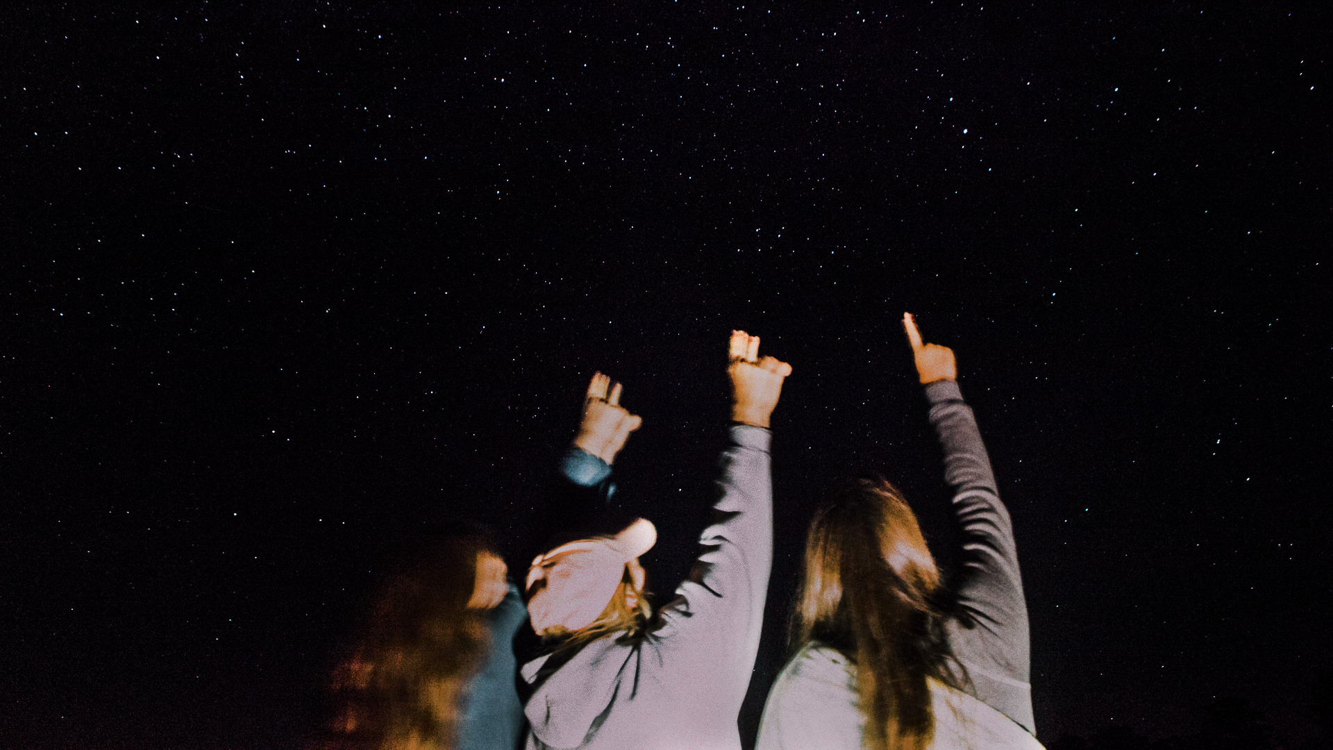People pointing at a dark sky